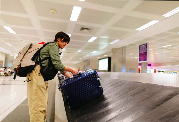 A young Japanese woman is retrieving her luggage at the airport baggage claim area