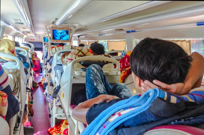 A passenger relaxing on a sleeper bus during a long journey in Asia