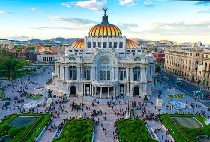 The breathtaking Palacio de Bellas Artes features a stunning white marble exterior, intricate metal designs, and colorful stained-glass windows, showcasing a fusion of Art Nouveau and Art Deco styles. Its beautiful gardens and the leisurely strolls of visitors contribute to the serene charm surrounding this cultural masterpiece.