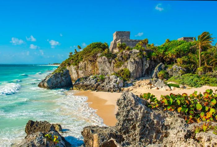 A rocky island bordered by sandy shores and gentle waves.