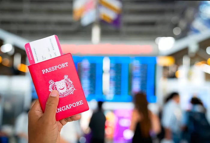 A hand holding passports and a boarding pass at the international airport.