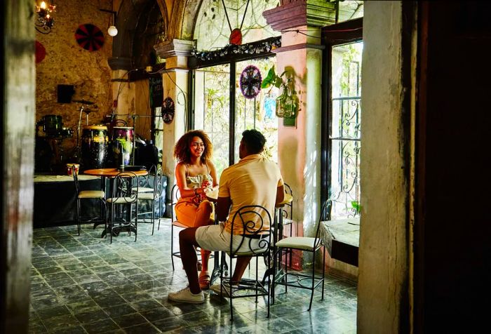 A man and a woman are having a relaxed conversation while seated in a café.