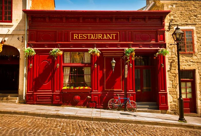 A charming French bistro with a bicycle leaning against its outer wall.