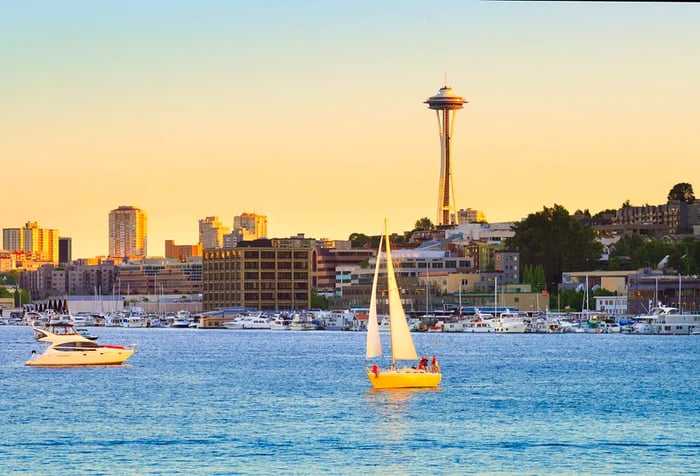 Boats gently drift on the serene waters of a peaceful lake, surrounded by a charming coastal town and a tall observation deck, all set against a beautiful twilight sky.