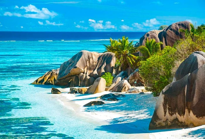 A breathtaking coastline features rocky formations amidst lush greenery, encircled by turquoise waters.