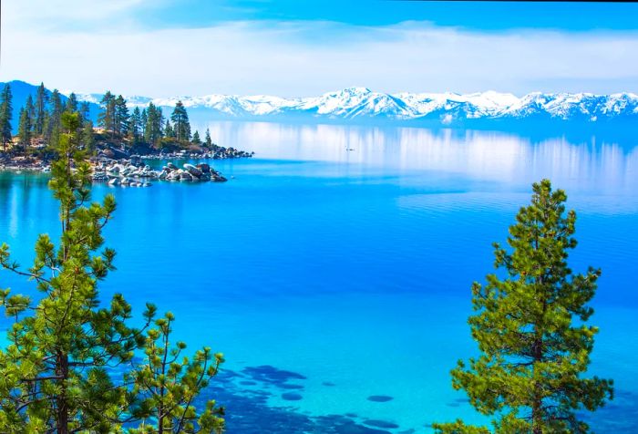 A lake with turquoise waters set against a backdrop of snow-capped mountains.