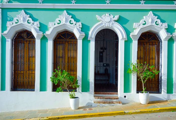 A building featuring light green walls and white arched trim around its windows and entrance.