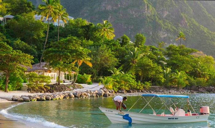 View along Jalousie Beach at sunset, with a water taxi in the foreground, Soufriere, St. Lucia