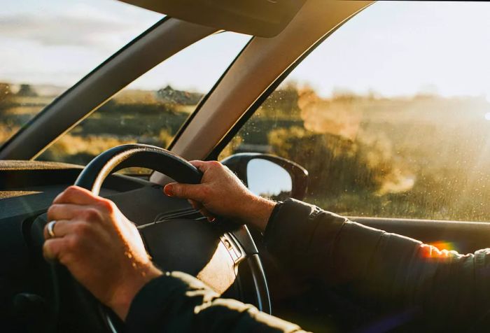 Hands gripping a car's steering wheel.