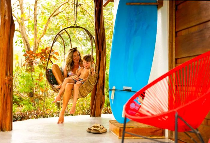 A woman and a young boy relaxing in a hammock on a porch.