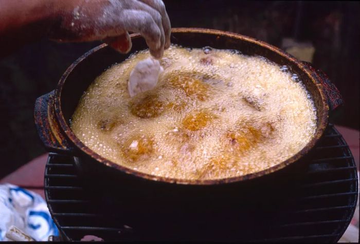 A chef drops conch fritters into sizzling oil for cooking.