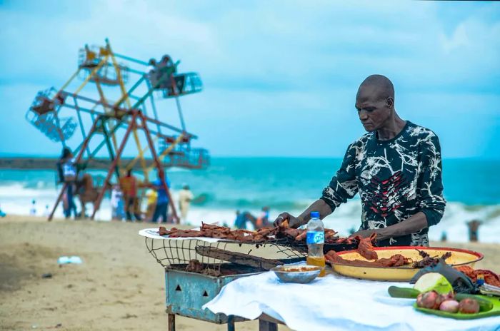 A man grilling roasted suya at Elegushi Beach in Lagos, Nigeria