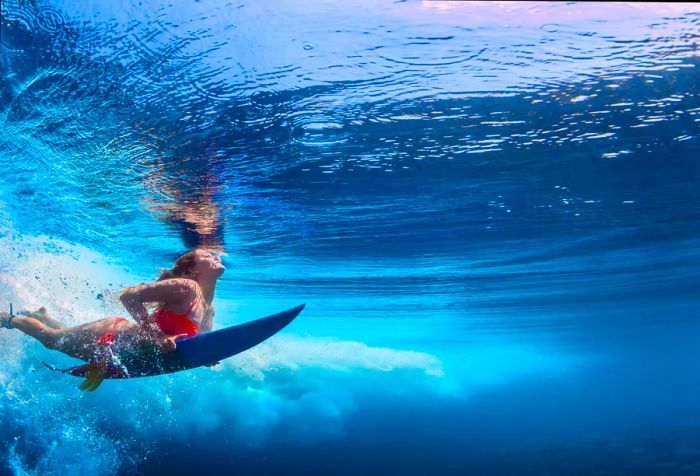 A woman in an orange bikini enjoys the sea while surfing.