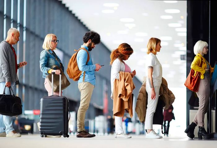 Travelers with their bags lined up at the airport check-in counters.