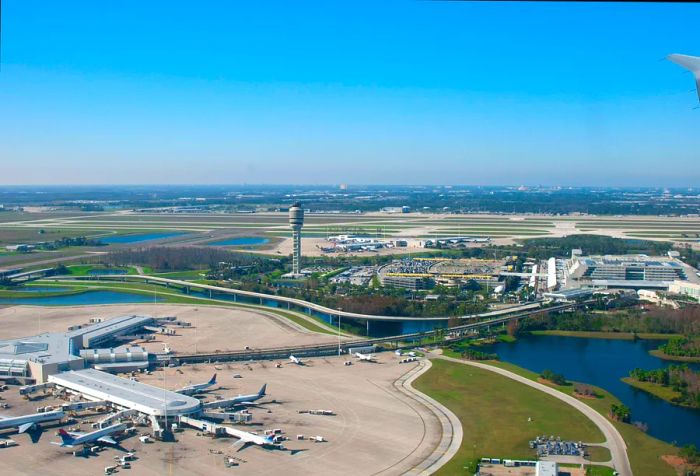 Aerial view of the airport complex showcasing a control tower and a small lake on a sunny day