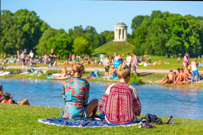 People basking in the summer sun, swimming in the Isar River, and unwinding on the lush grounds of Englischer Garten in Munich, Germany