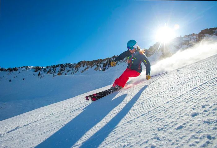 A woman skis through soft powder snow in the mountainous terrain.