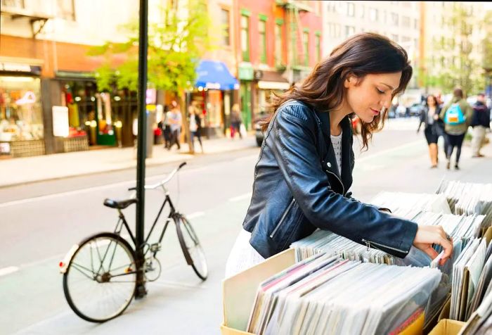 A woman peruses a selection of magazines displayed outside a shop.