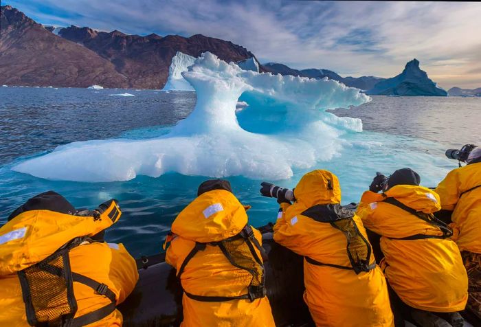 An expedition clad in yellow jackets capturing research and images of icebergs in Scoresbysund, Greenland.