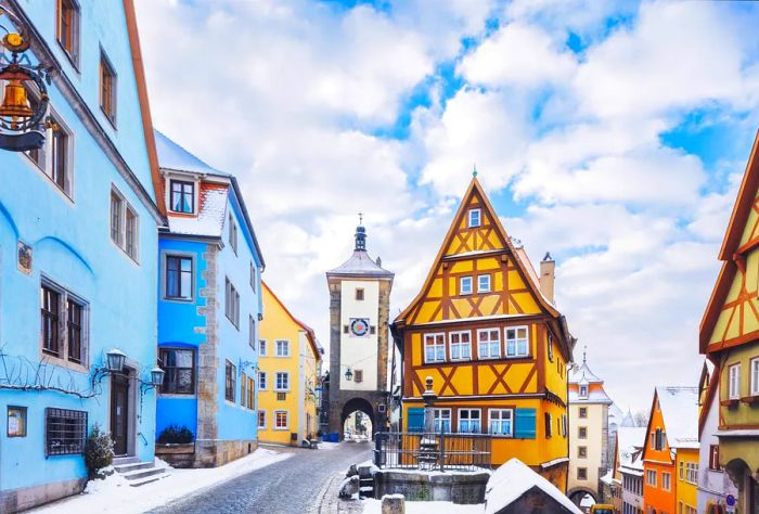 Charming half-timbered houses line a cobblestone street with a snowy walkway.