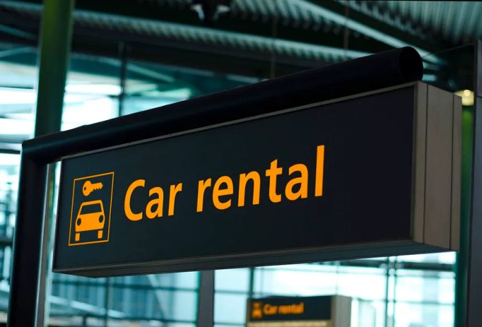 A black sign indicating car rentals hangs at the airport.