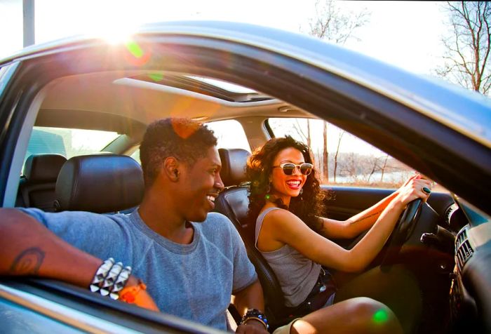 A woman driving a car with a male passenger seated beside her.