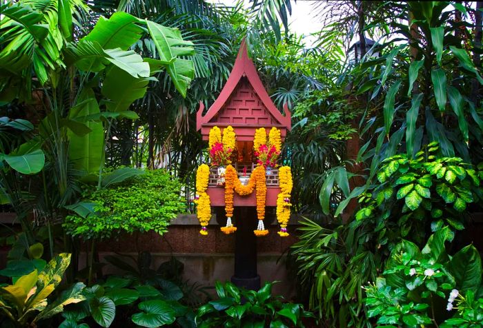 Yellow flower offerings displayed at the Spirit House within the gardens.