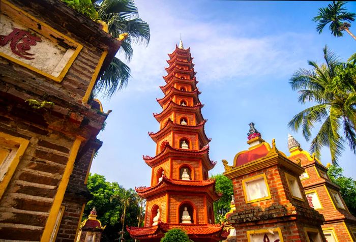 A beautifully tiered red brick pagoda nestled in a park surrounded by palm trees.