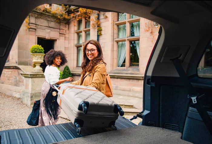 Two friends arrive at a luxury hotel, unloading their luggage from the trunk of their car.