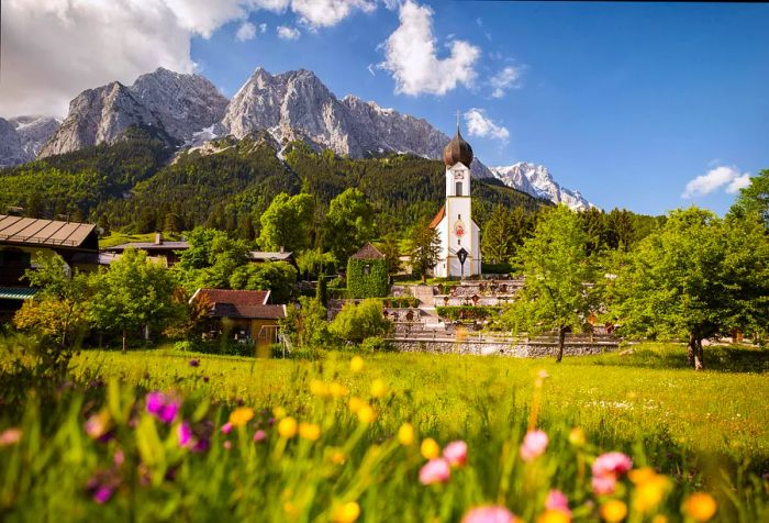 A white church with an onion-shaped dome overlooks the town, framed by a lush green lawn.