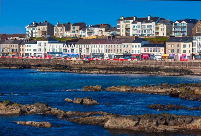 Two picturesque rows of houses cascade down a hillside overlooking the seaside.