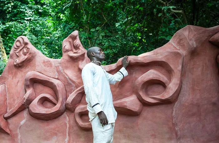 A man stands beside a sculpture in the sacred grove during the Osun-Osogbo Festival in Osogbo, Nigeria.