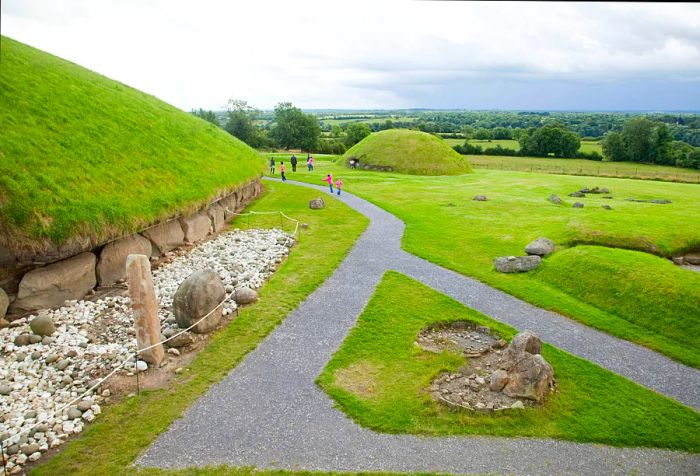 A narrow pathway meanders across a verdant lawn dotted with grassy mounds.