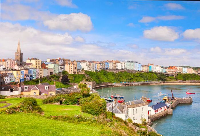 A charming walled harbor town featuring a concrete pier and surrounded by vibrant, colorful buildings.