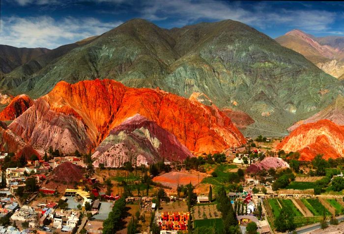 A quaint town nestled in the valley, framed by a stunning, multi-colored mountain range.