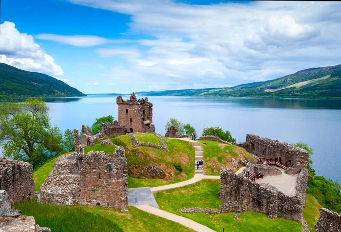 Remains of a fortified stone castle standing on a hill above a lake.