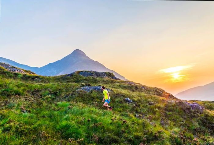 A man in a yellow shirt jogging along a lesser-known trail at sunset.