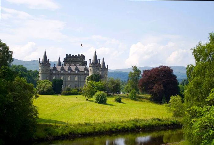 A view of a beautifully maintained castle alongside a river.