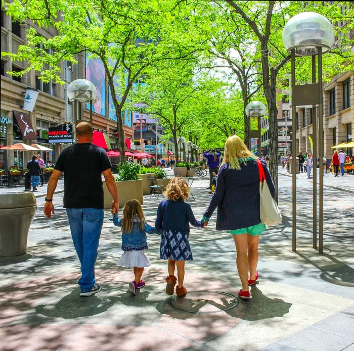 A family of four seen from behind as they stroll through downtown Denver