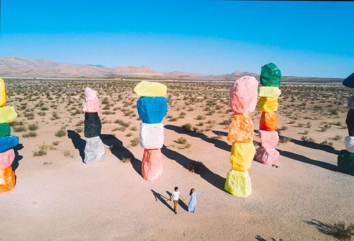 A couple strolls among the colorful stacks of painted boulders at Seven Magic Mountains.