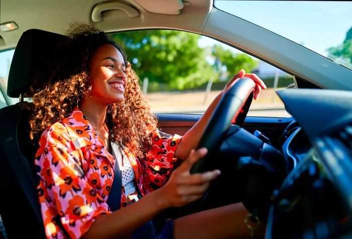 a cheerful woman in a vibrant outfit sitting in the driver's seat of a car