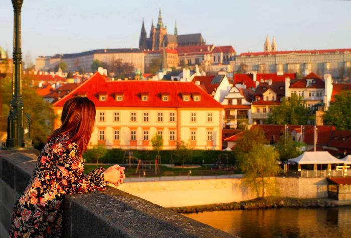 A woman rests against a bridge wall, captivated by the magnificent architecture before her.