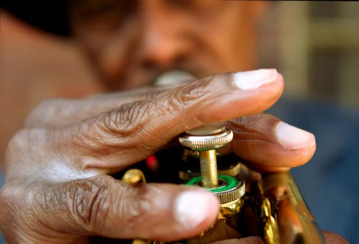 An older gentleman wearing a hat playing a trumpet.