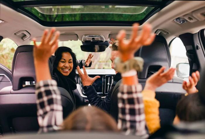 A family of four joyfully celebrating in the car, eager to embark on their road trip.