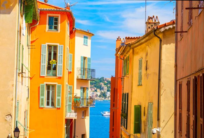 Amidst vibrant buildings, a picturesque scene of boats gliding across serene blue waters, framed by a hillside dotted with structures and greenery.