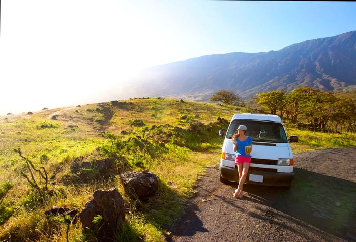 A woman pauses to enjoy a fresh coconut while cruising along the road to Hana.