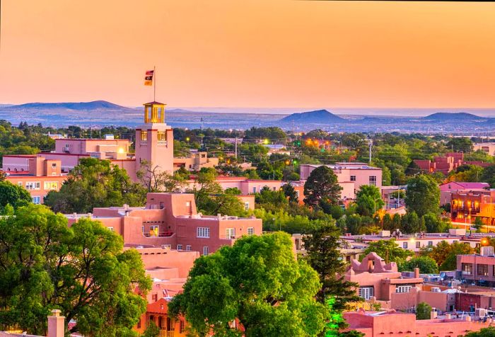 A tower with a flag stands tall over a residential area surrounded by lush greenery beneath an orange sky.