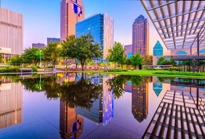 A tranquil pool within a wooded park mirrors the towering skyscrapers of the city.