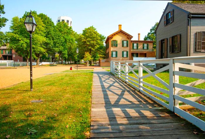 A wooden walkway winds along a street with a white fence and shadows in New Salem, Springfield, Illinois, USA.