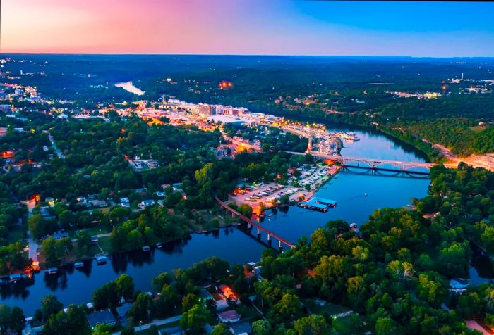 Two bridges span a lake, linking neighborhoods adorned with trees.